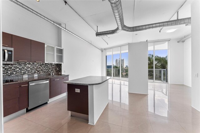 kitchen featuring decorative backsplash, modern cabinets, stainless steel appliances, dark brown cabinets, and a sink