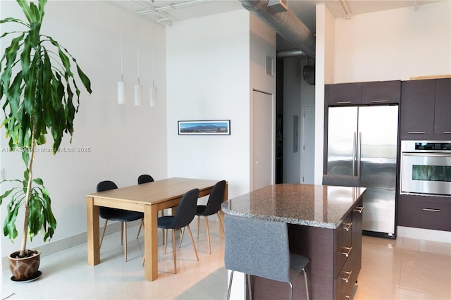 kitchen featuring visible vents, modern cabinets, a kitchen island, appliances with stainless steel finishes, and stone counters