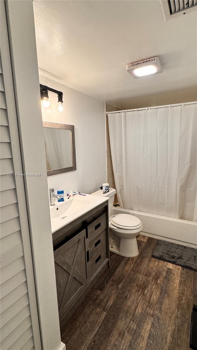 full bathroom featuring vanity, hardwood / wood-style flooring, shower / bath combination with curtain, and toilet