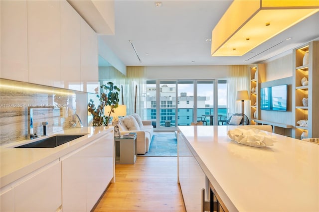 kitchen featuring tasteful backsplash, sink, light hardwood / wood-style flooring, and white cabinets