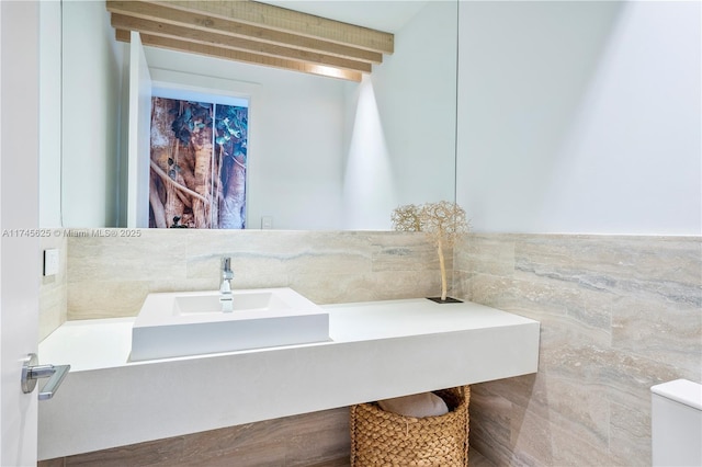 bathroom featuring sink and tile walls