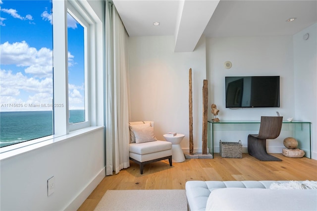 living area featuring a water view and light hardwood / wood-style flooring