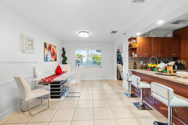 dining space featuring light tile patterned floors, baseboards, and visible vents