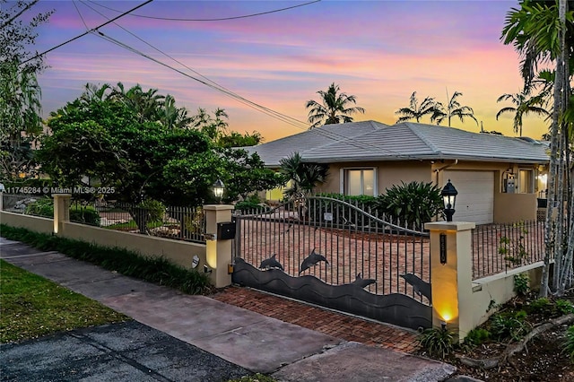 view of front of house featuring an attached garage, a fenced front yard, stucco siding, and a tile roof