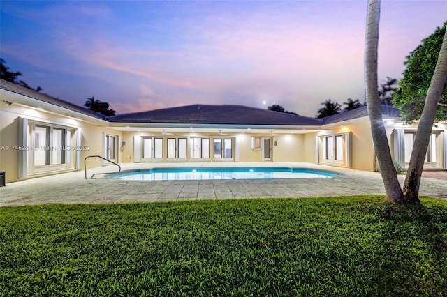 back house at dusk with a patio area, french doors, and a lawn