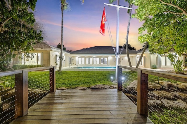 deck at dusk featuring an outdoor pool