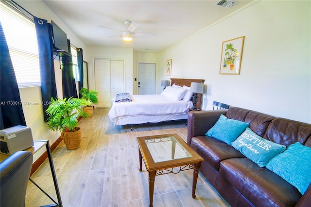 bedroom with ceiling fan, ornamental molding, a closet, and light hardwood / wood-style flooring