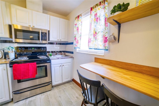 kitchen with white cabinetry, stainless steel appliances, sink, and tasteful backsplash