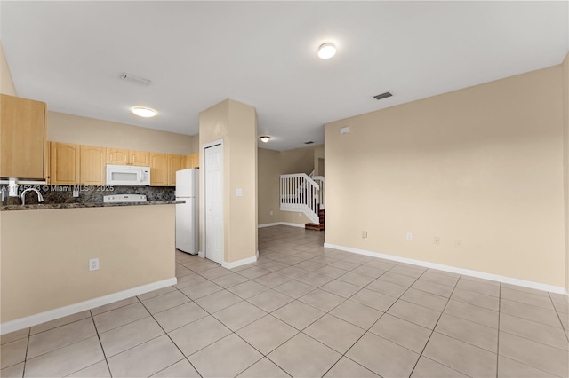 kitchen featuring sink, tasteful backsplash, light tile patterned floors, light brown cabinets, and white appliances