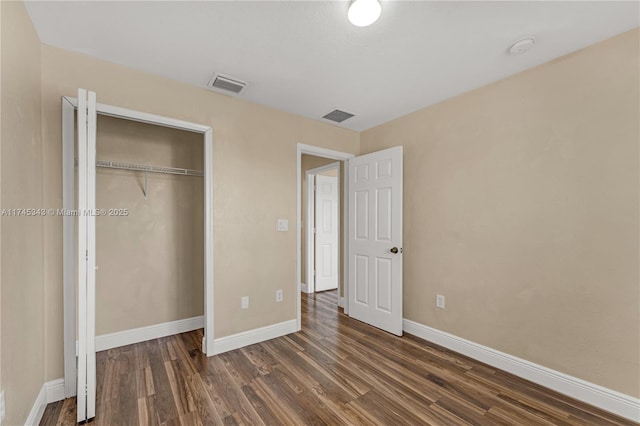 unfurnished bedroom featuring dark hardwood / wood-style flooring and a closet