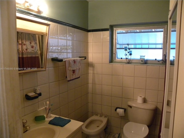 bathroom featuring a bidet, tile walls, vanity, and toilet