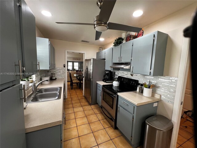 kitchen with under cabinet range hood, electric range, a sink, visible vents, and freestanding refrigerator