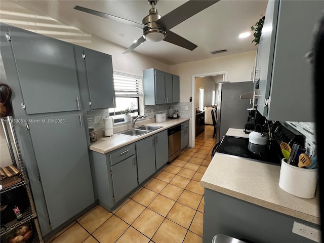 kitchen featuring light tile patterned floors, tasteful backsplash, stainless steel appliances, light countertops, and a sink