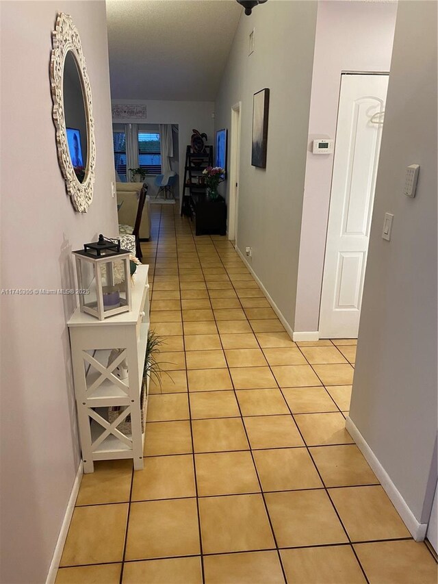 corridor featuring light tile patterned flooring and baseboards