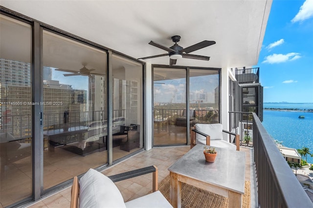 balcony featuring a water view and a ceiling fan