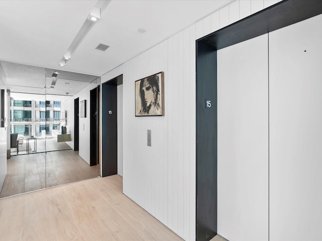 hallway with elevator, light wood-style flooring, and visible vents