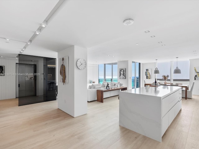 kitchen with a spacious island, light countertops, hanging light fixtures, white cabinets, and modern cabinets