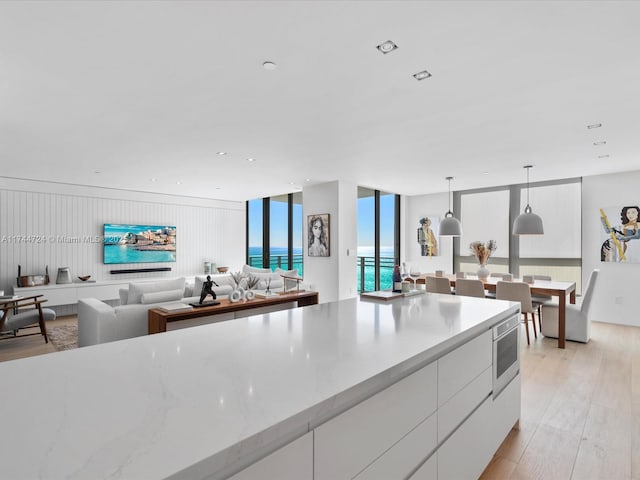 kitchen with white cabinets, modern cabinets, open floor plan, decorative light fixtures, and light wood-style floors