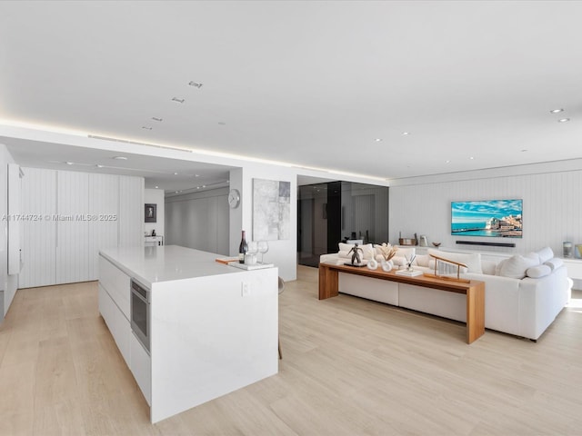 kitchen featuring white cabinets, modern cabinets, open floor plan, a center island, and light countertops