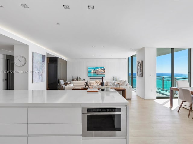 kitchen with modern cabinets, open floor plan, oven, light countertops, and white cabinetry