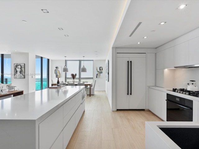 kitchen with black appliances, modern cabinets, a kitchen island, and white cabinets