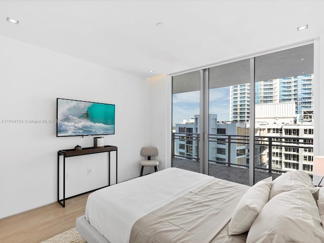bedroom with light wood-type flooring, access to exterior, floor to ceiling windows, and recessed lighting