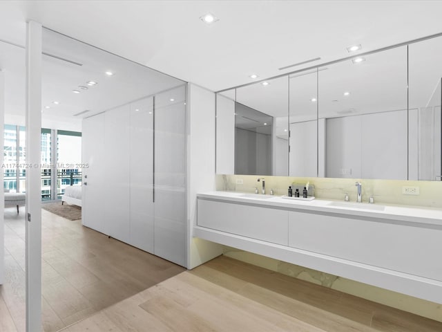 full bath featuring double vanity, wood finished floors, a sink, and ensuite bathroom