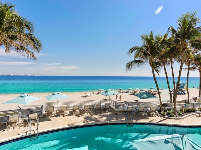 view of swimming pool with a water view and a view of the beach