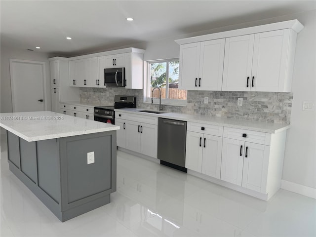 kitchen with sink, white cabinetry, a center island, appliances with stainless steel finishes, and backsplash