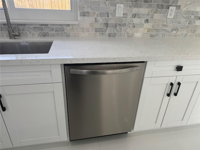 room details featuring stainless steel dishwasher, light stone countertops, sink, and white cabinets