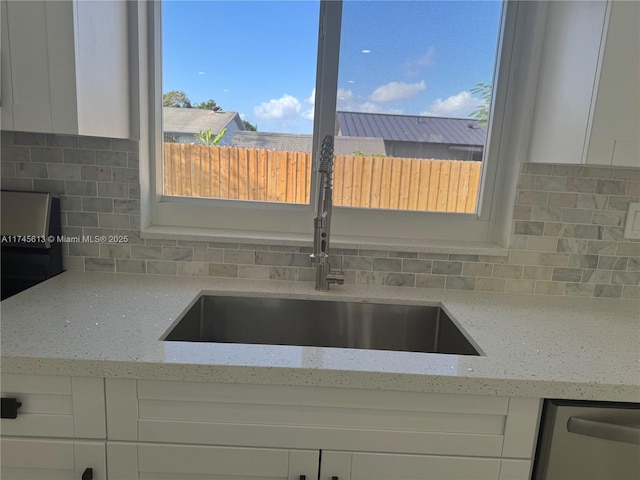 kitchen featuring white cabinetry, backsplash, and light stone counters