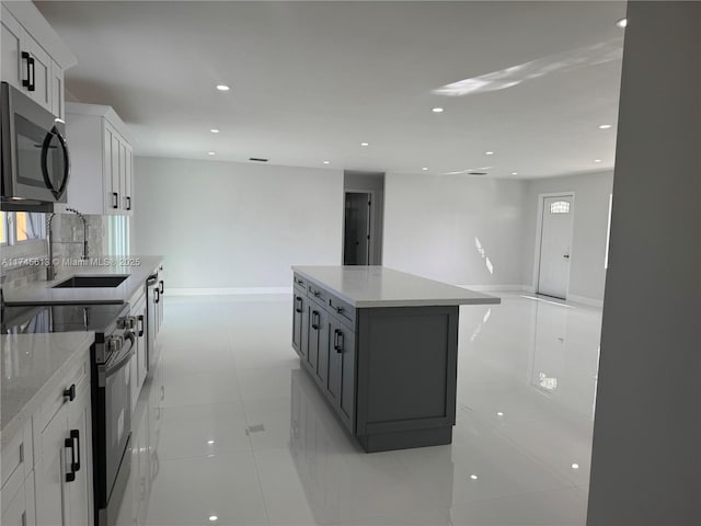 kitchen featuring black electric range oven, sink, a kitchen island, light stone countertops, and white cabinets