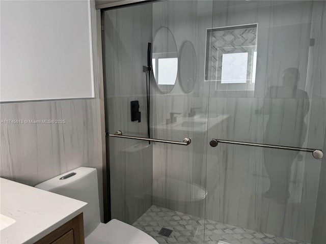 bathroom with toilet, vanity, and a shower with shower door