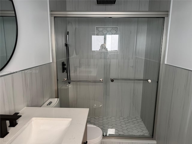 bathroom with a shower with door, vanity, and toilet