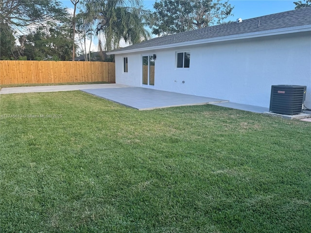 rear view of house featuring a lawn, central AC unit, and a patio area