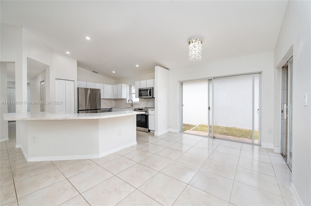 kitchen featuring white cabinetry, decorative backsplash, a center island, and appliances with stainless steel finishes