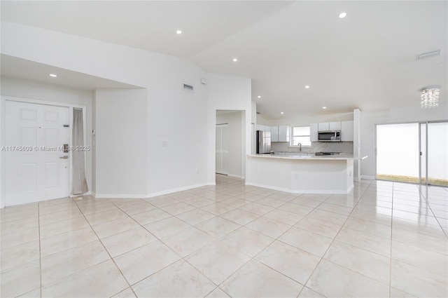 unfurnished living room with light tile patterned flooring, vaulted ceiling, and sink