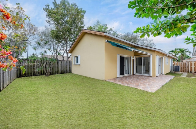 rear view of property featuring central AC unit, a yard, and a patio