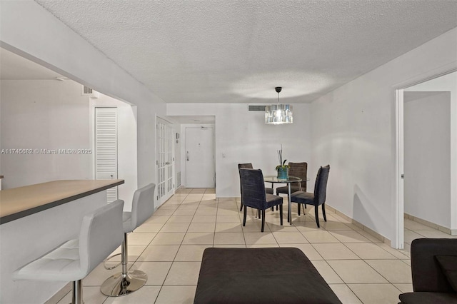 dining room featuring light tile patterned floors, a notable chandelier, and a textured ceiling