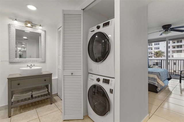 laundry room with stacked washer / drying machine, light tile patterned floors, sink, and ceiling fan