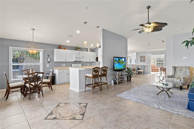 interior space with white cabinetry, light tile patterned floors, lofted ceiling, and a kitchen bar