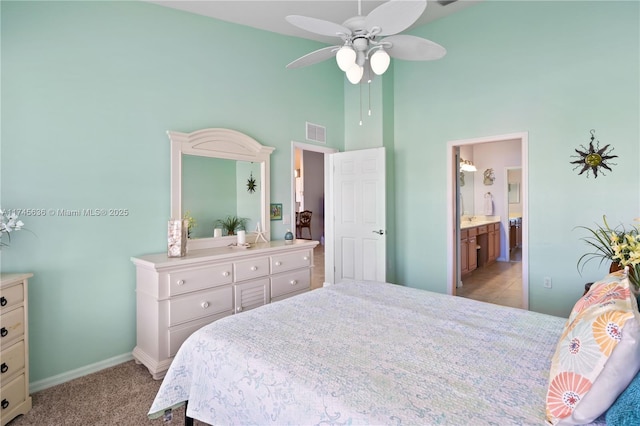 bedroom featuring light carpet, high vaulted ceiling, and ensuite bathroom