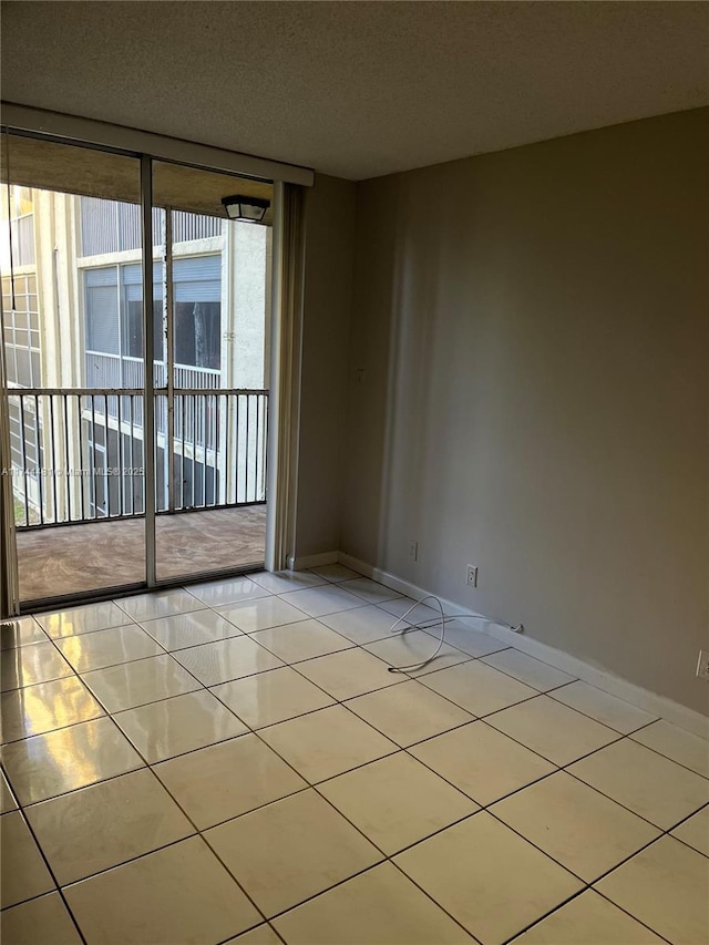 unfurnished room with a wall of windows, a textured ceiling, and light tile patterned floors