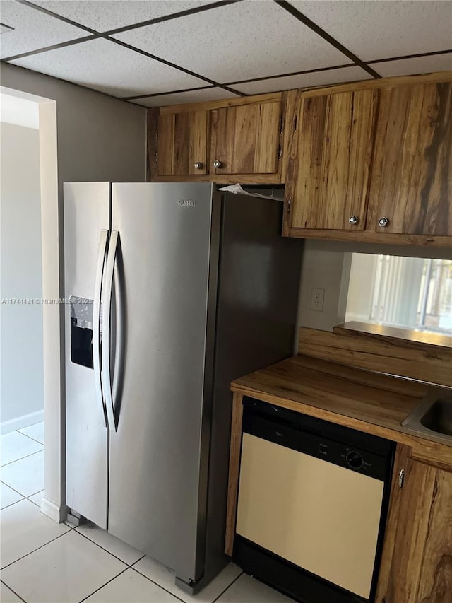 kitchen featuring stainless steel refrigerator with ice dispenser, a paneled ceiling, dishwashing machine, and light tile patterned flooring