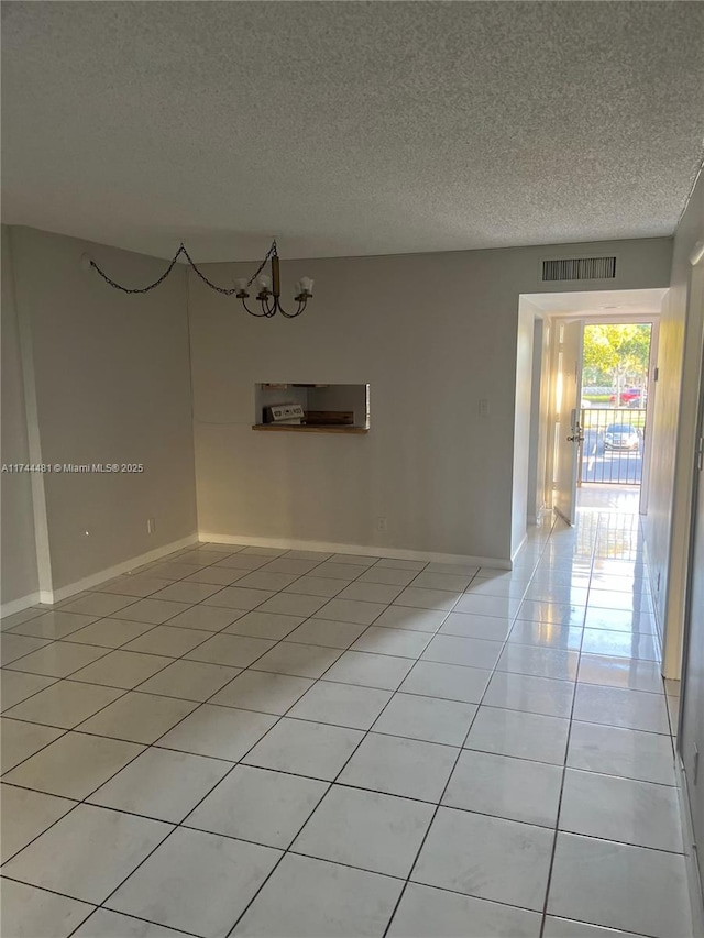 spare room featuring light tile patterned floors and a textured ceiling