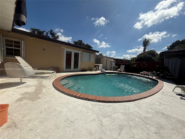 view of pool featuring a fenced in pool, a fenced backyard, french doors, a patio area, and a shed