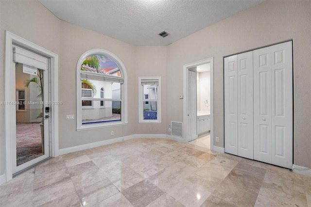 unfurnished bedroom with connected bathroom, a textured ceiling, and a closet