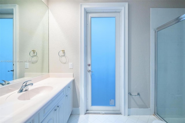 bathroom featuring a shower with door and vanity