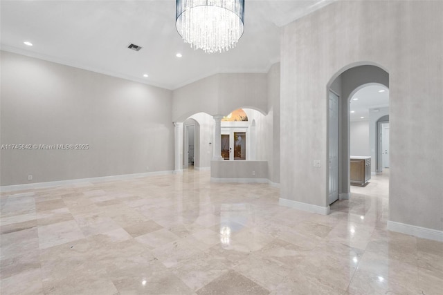 empty room with crown molding, a notable chandelier, and a high ceiling