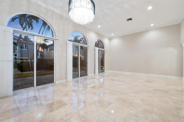 spare room with a notable chandelier, crown molding, french doors, and a high ceiling